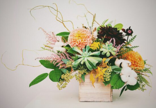 A beautiful bouquet of orange and pink flowers, including dahlias, in a pale basket