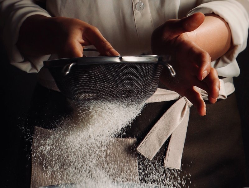 A person sieving flour