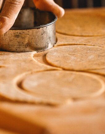 close up on buttery floury pastry rolled out on a board and being cut into circles