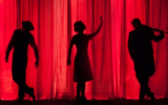 3 people in silhouette posing on stage