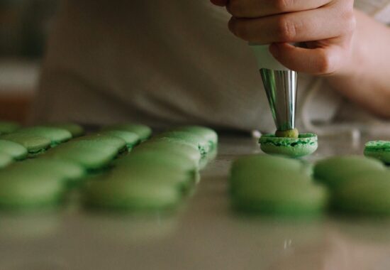 Someone pipes green macaroons
