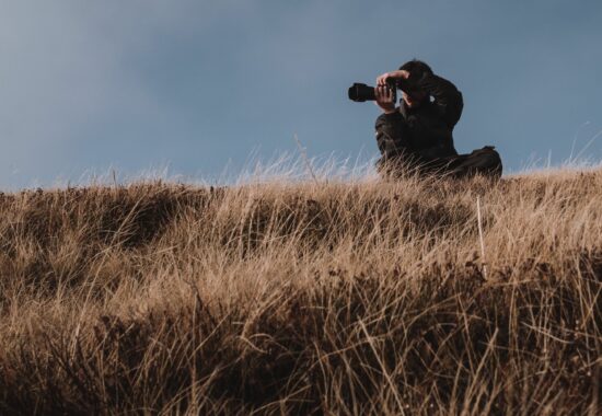A photographer crouches in long grass