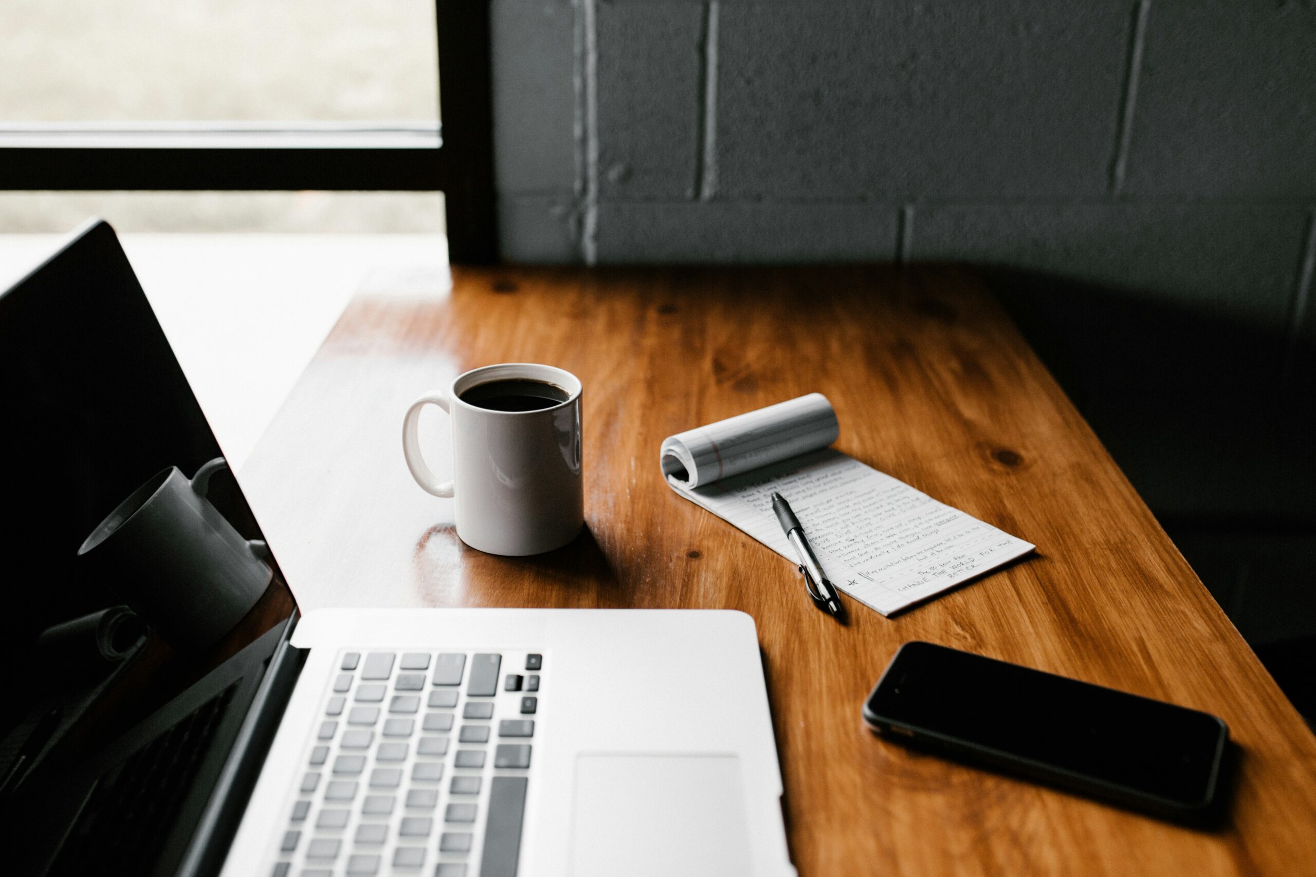 A coffee cup and laptop on a table