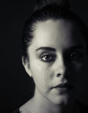 A person stares direct to camera with a tear on their eye