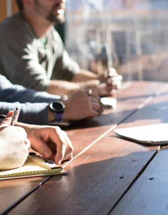 people writing notes on a woodern desk