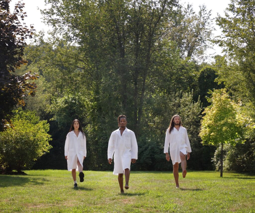 3 people walking barefoot across grass